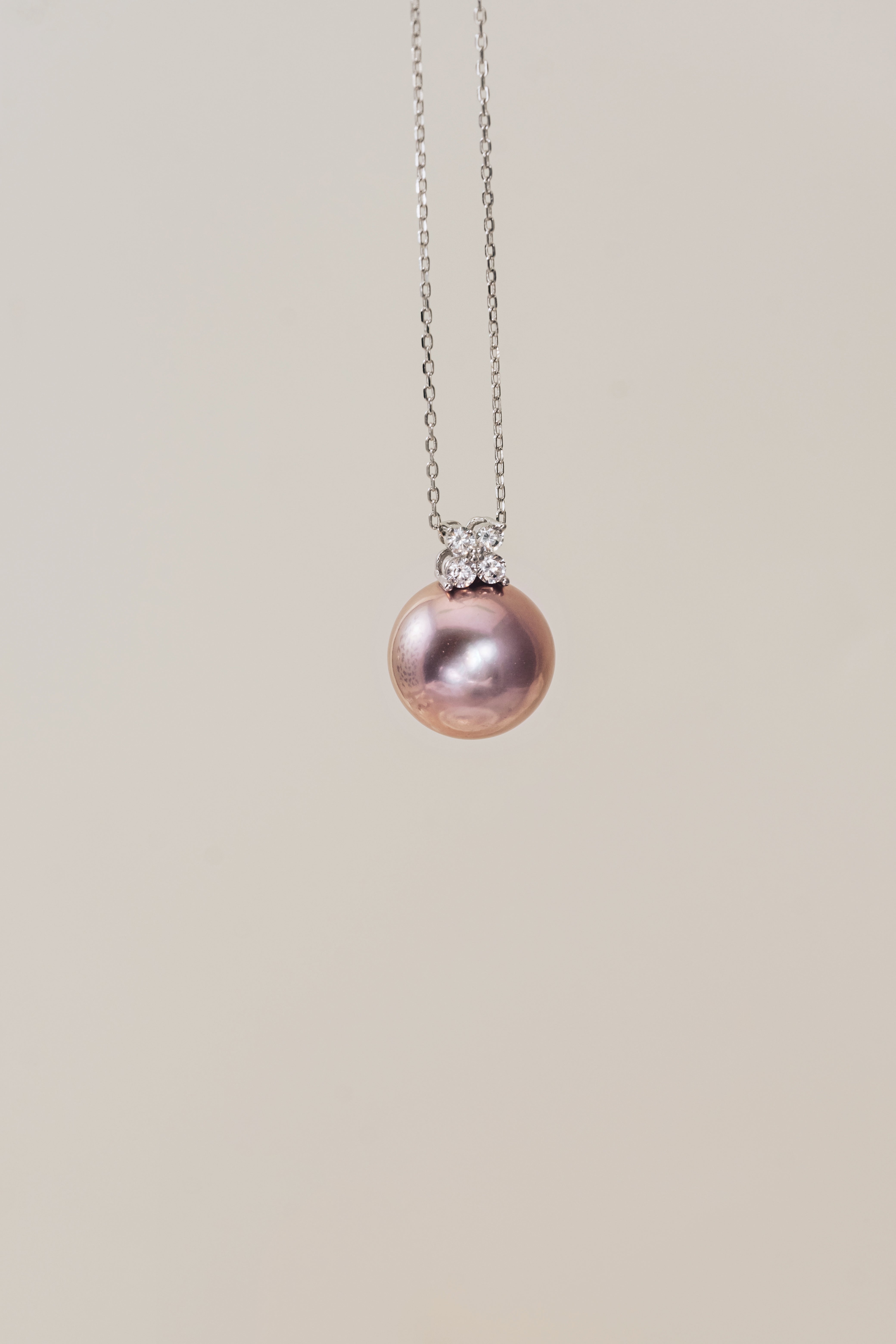 Necklace with a pink pearl pendant on a beige background